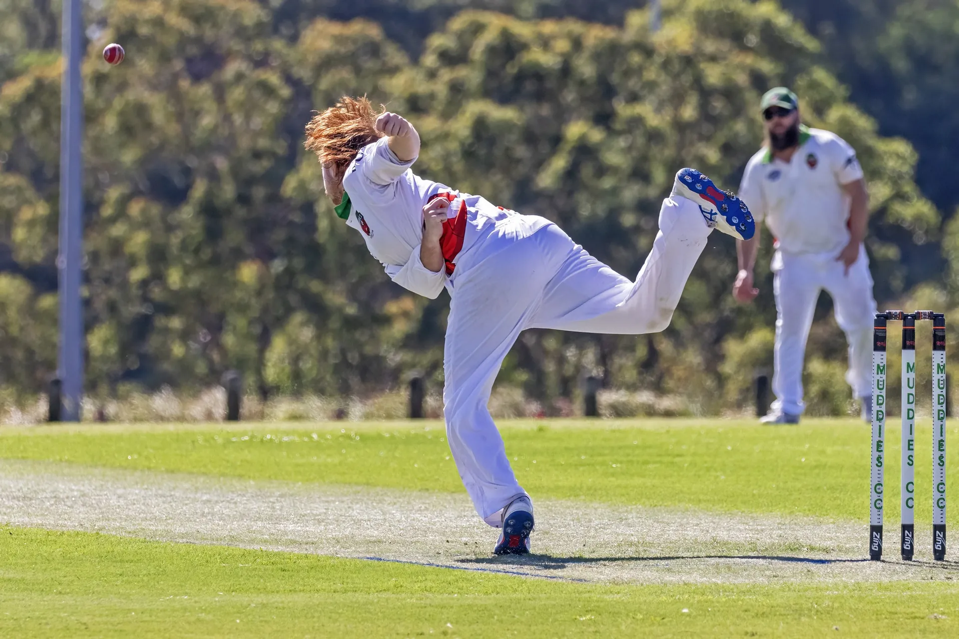 Muddies bowler in delivery stride with the ball mid-air