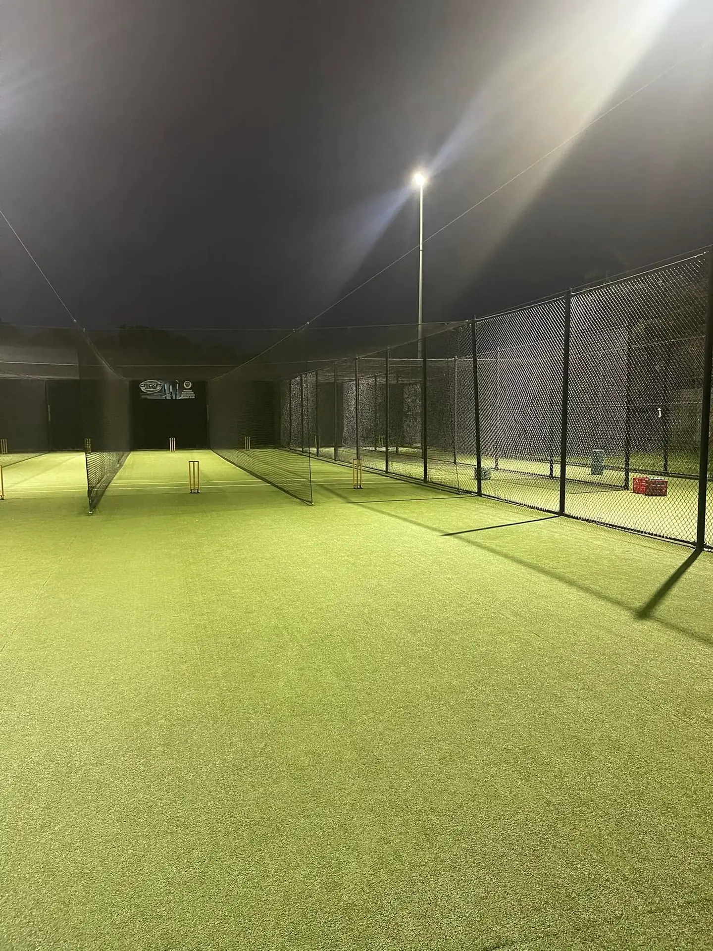 Empty Muddies practice nets lit by floodlights at night